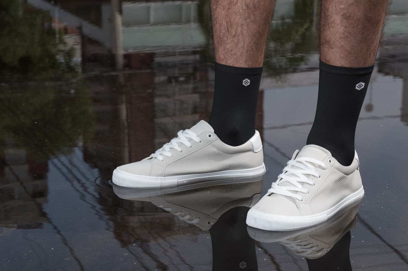 Medias Sockets negras puestas, con zapatillas blancas sobre asfalto mojado